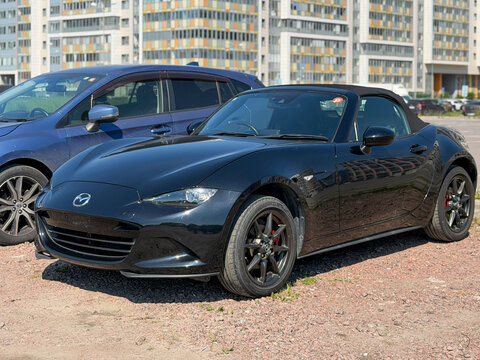 A stylish Mazda MX-5 RF Miata Sport Tech, two door sports car convertible black color, in a carpark at the city. Exterior of a Mazda MX-5 Miata RF Roadster fastback model. JDM car. 