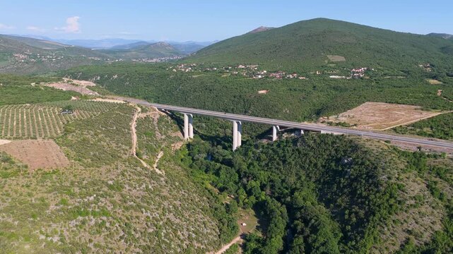 Modern highway bridge crossing a green mountain valley captured from an aerial drone perspective