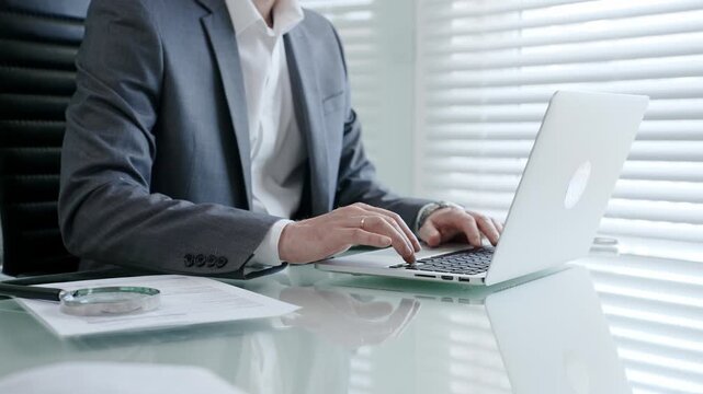 Business professional hands typing on a laptop keyboard during office work, creating a document, sending an email, or performing online research at his modern desk