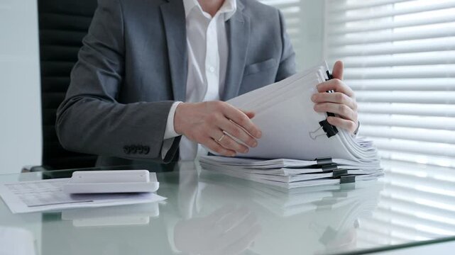 Businessman's hands are busy managing and organizing a large stack of financial papers and business documents
