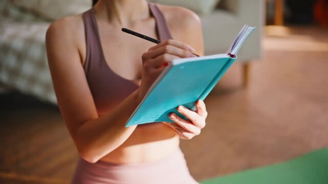 Close up woman writing notes diary after yoga workout, thoughtful fitness girl