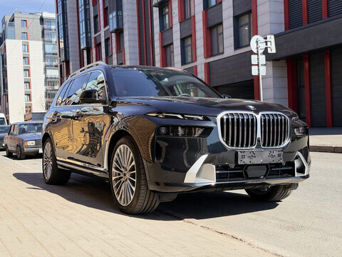 Black BMW X7 G07 in the street parking lot. The modern vehicle exterior SUV car BMW X7 G07. Premium Germany SUV Car BMW X7 G07 summer day in the street parking.