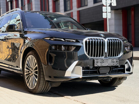Black BMW X7 G07 in the street parking lot. The modern vehicle exterior SUV car BMW X7 G07. Premium Germany SUV Car BMW X7 G07 summer day in the street parking.