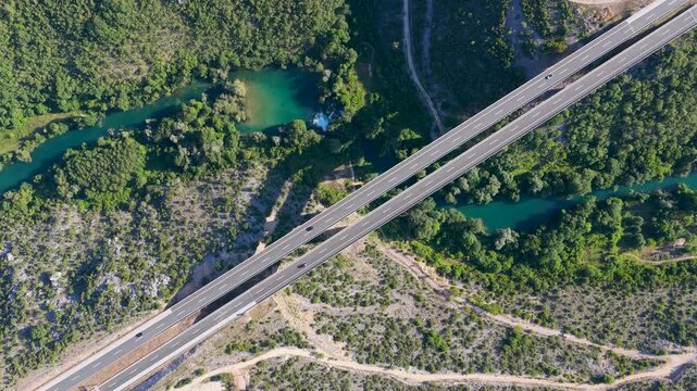 Top down drone view of modern highway bridge crossing a forested river valley