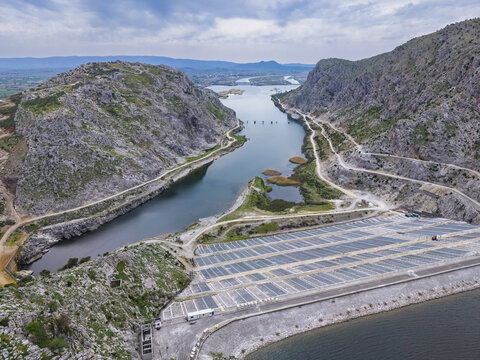 Aerial view of the Vau i Dejes Hydroelectric Power Station with its artificial lake and solar panel arrays construction between rugged rocky mountains in Vau i Dejes, Qarku i Shkodres, Albania.