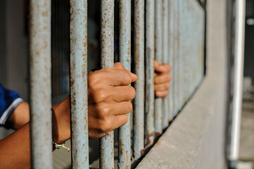 Obraz premium prisoner's hands behind bars with black background