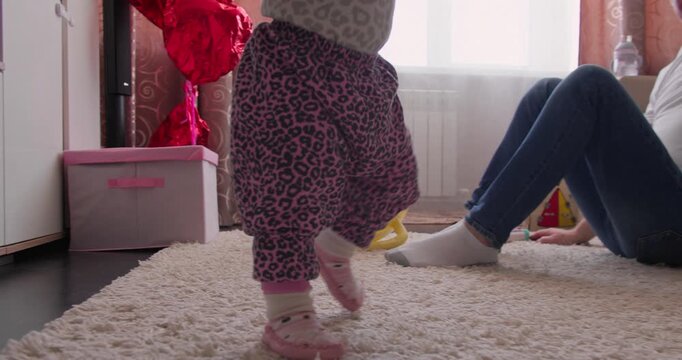 Close-up of toddler feet during early walking practice indoors. First steps milestone and balance development in early childhood