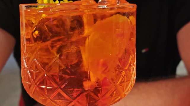 glass with orange cocktail. Stirring ice with fruit in a glass with an aperol cocktail