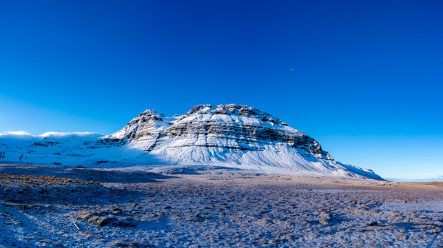 Aerial view of Keilir mountain covered in snow under a clear blue sky in the volcanic landscape of Grindavik, Sveitarfelagid Vogar, Iceland.