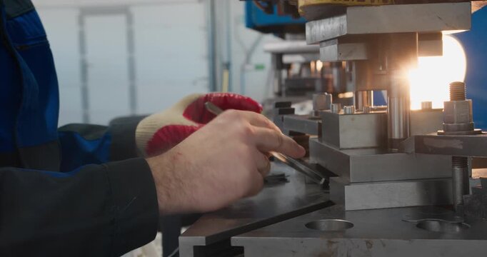 Punch press tooling forms identical metal parts for serial production. Manufacturing operation captured in close-up