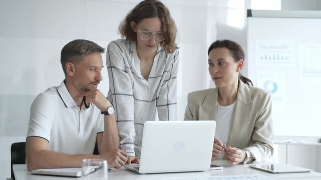 Business team collaborating and analyzing data on a laptop during a productive meeting in a modern office, fostering teamwork and strategic decision making