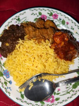 Nasi Minyak served with ayam masak merah, daging masak hitam, and chicken rendang, traditional Malaysian cuisine
