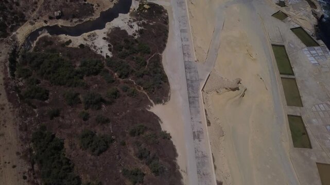 Xwejni s centuries-old salt pans unfold along the rugged coast of Zebbug, Gozo, geometric pools and vivid Mediterranean blues in a sweeping summer Aerial view. High quality 4k footage