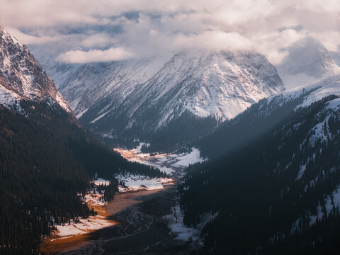 Aerial view of Boris Yeltsin Peak rising above the snow-covered valley and dense pine forests in Jety-Oguz, Issyk-Kul Region, Kyrgyzstan.
