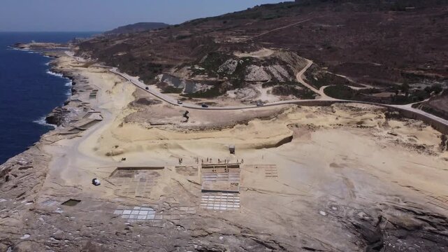 Xwejni s centuries-old salt pans unfold along the rugged coast of Zebbug, Gozo, geometric pools and vivid Mediterranean blues in a sweeping summer Aerial view. High quality 4k footage
