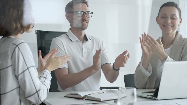 Professional team applauding, celebrating collaborative success and recognizing outstanding performance during corporate meeting, expressing shared workplace achievement