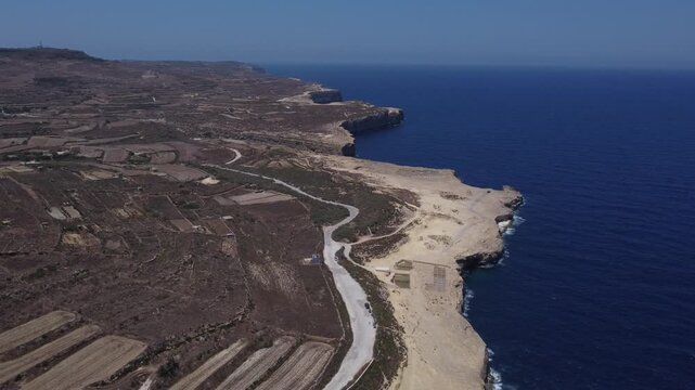Xwejni s centuries-old salt pans unfold along the rugged coast of Zebbug, Gozo, geometric pools and vivid Mediterranean blues in a sweeping summer Aerial view. High quality 4k footage