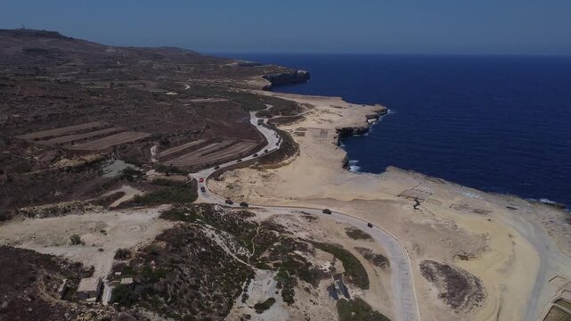 Xwejni s centuries-old salt pans unfold along the rugged coast of Zebbug, Gozo, geometric pools and vivid Mediterranean blues in a sweeping summer Aerial view. High quality 4k footage