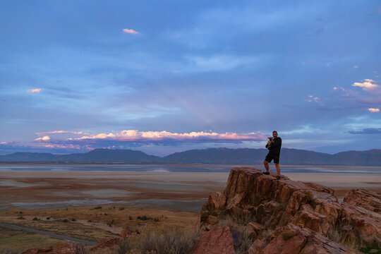 Man holding a small dog overlooking the sunset over The Great Salt Lake at Antelope Island State Park, Utah, USA