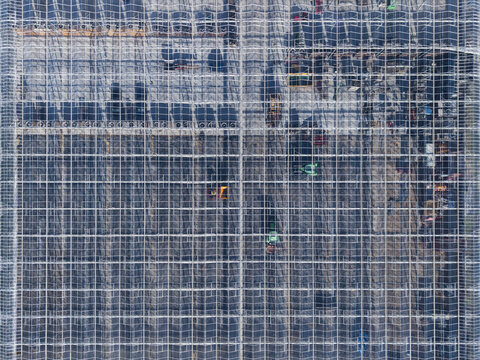 Aerial view of a large glass greenhouse complex with metal framework and agricultural machinery in Heerhugowaard, North Holland, Netherlands.
