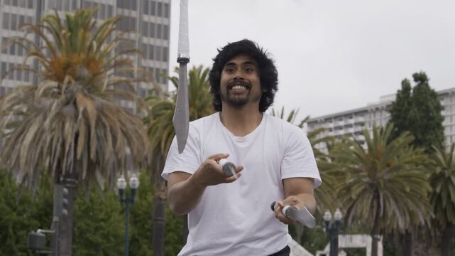 Juggler Smiling As He Juggles Knives in San Francisco Plaza - Medium Slow Motion Shot