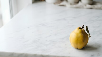 A single whole quince with subtle fuzz resting in the lower right corner of a large white marble surface, most of the frame left empty as negative space for seasonal fruit or artisanal food copy.