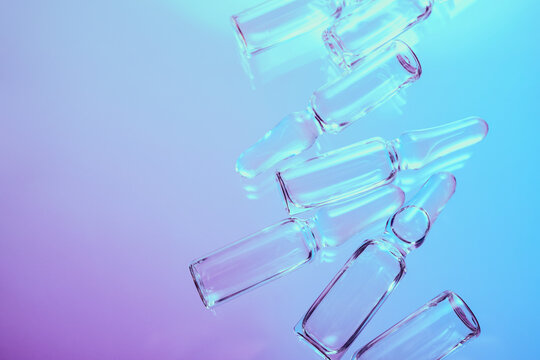Glass ampoules reflecting neon light representing medical science and pharmaceutical research