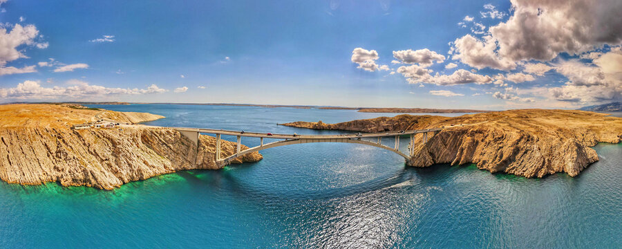 Aerial view of Pag Bridge spanning the rocky coastline and turquoise waters of the Adriatic Sea in Pag, Zadar County, Croatia.