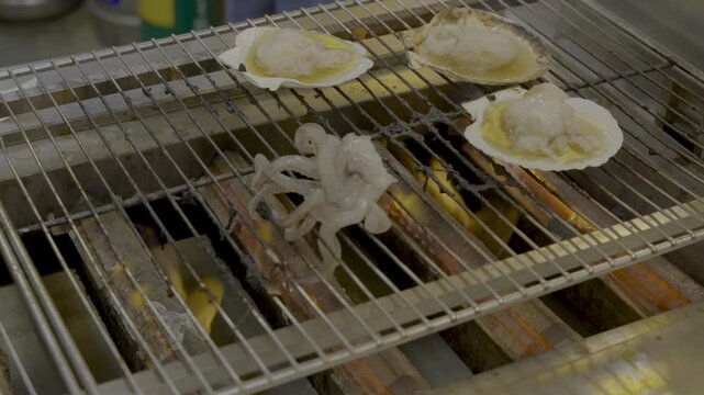 市場でイカの足が踊りホタテ貝を焼いている光景
