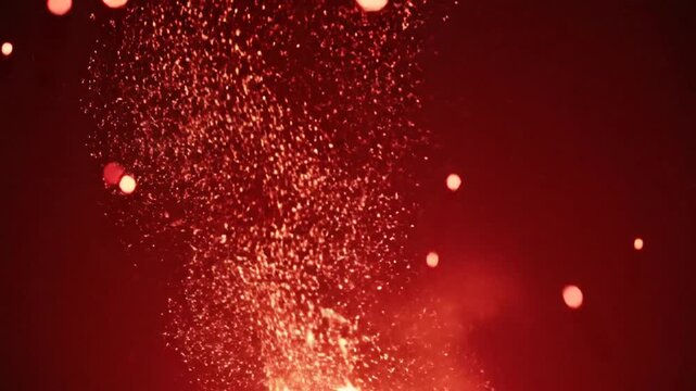 Vibrant red sparks explode in a dynamic display of firework particles against a dark background.