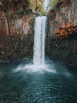 Aerial view of Abiqua Falls cascading over dramatic basalt columns into a deep pool surrounded by lush forest in Marion County, Oregon, United States.