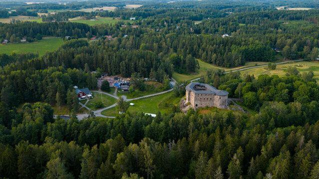 Aerial view of Raseborg Castle Ruins surrounded by dense green forests and open fields in Snappertuna, Nyland, Finland.