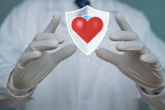 Doctor hands protecting a glowing heart with shield symbol representing cardiovascular health, medical insurance, preventive healthcare, patient safety, and digital health protection.