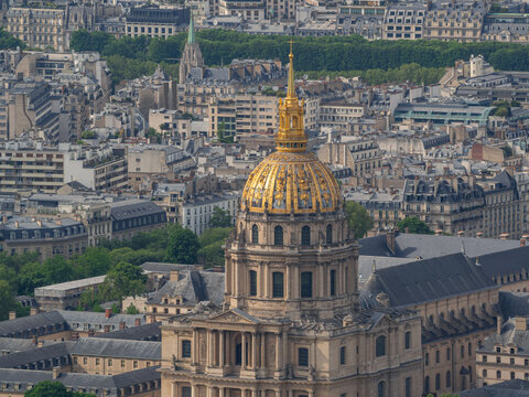 Aerial view of the golden dome of Les Invalides surrounded by the historic architecture and dense urban rooftops of Paris, Ile-de-France, France.