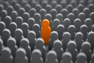 Fototapeta premium orange figure stands out from grey crowd