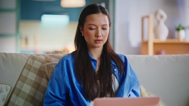 Asian freelancer typing pink laptop sofa home. Closeup woman hands remote work