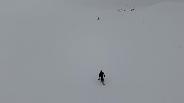 Aerial drone view of a skier riding down the slopes in Gudauri, Georgia in March. Cinematic winter sports shot under a cloudy sky.