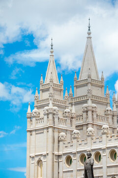 Vertical architectural view of the stone spires of the Salt Lake Temple against clouds