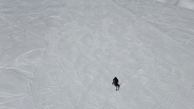 Aerial drone view of a skier carving down the slopes in Gudauri, Georgia in March. Cinematic winter sports shot on a bright sunny day.