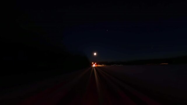 Back car window view of long exposure time laps of the highway in the city during road trip in Barrie lake Simcoe area. City at night timelapse. Driving a car vehicle back trunk POV view.