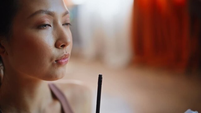 Asian woman journaling home holding pen. Close up portrait writing notes.