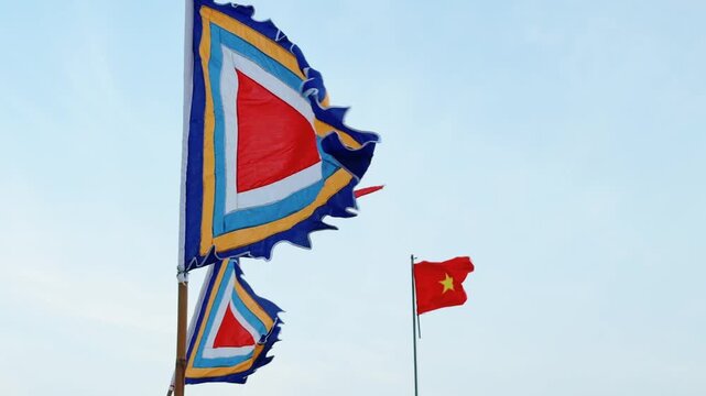 Traditional Vietnamese Festive Pennant and National Flag waving in the strong wind with blue sky in the background