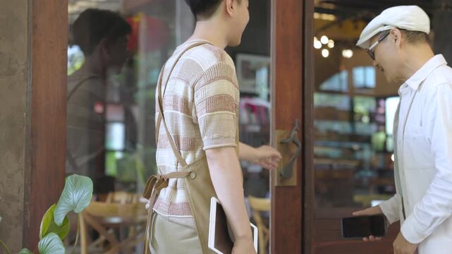 Cafe worker or young small business owner startup changing sign from closed to open at glass door, retail cafe and restaurant shop reopening process and welcoming customers in coffee shop environment.