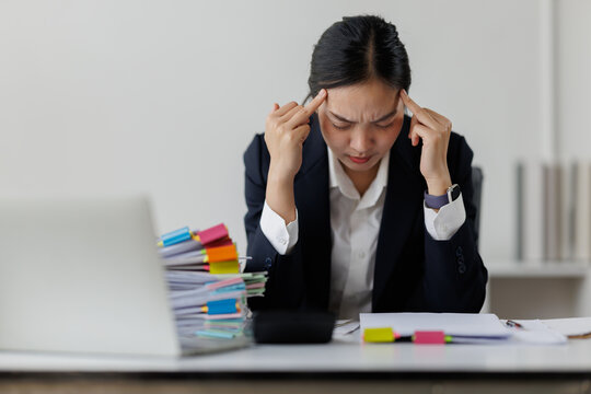Asian businesswoman experiencing stress, headache, and burnout at office