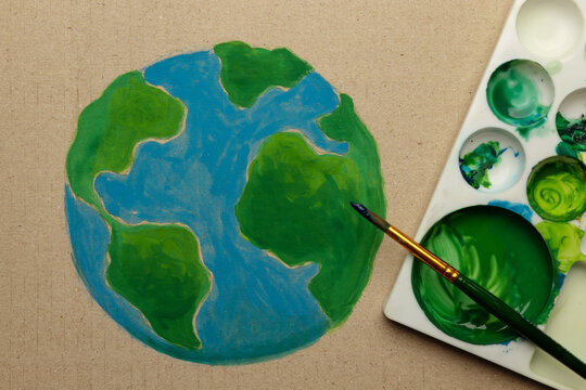 Earth Day painting activist scene with brush coloring green land on handmade globe