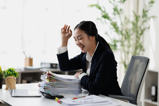 Asian businesswoman celebrating success with paperwork in office