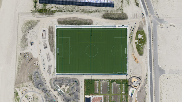 Aerial view of the Strandeiland soccer field surrounded by sandy terrain and recreational paths in Amsterdam, Noord-Holland, Netherlands.