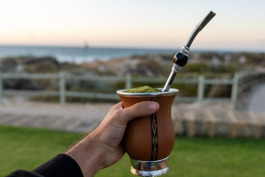 Hand holding yerba mate gourd on a beach