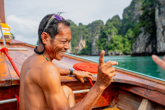 Smiling local man enjoying long-tail boat trip in thailand