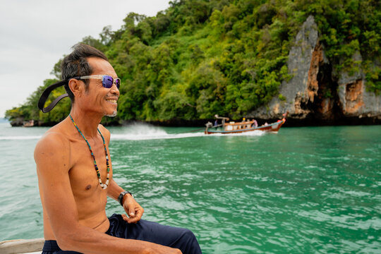 Smiling man wearing sunglasses on a longtail boat in thailand
